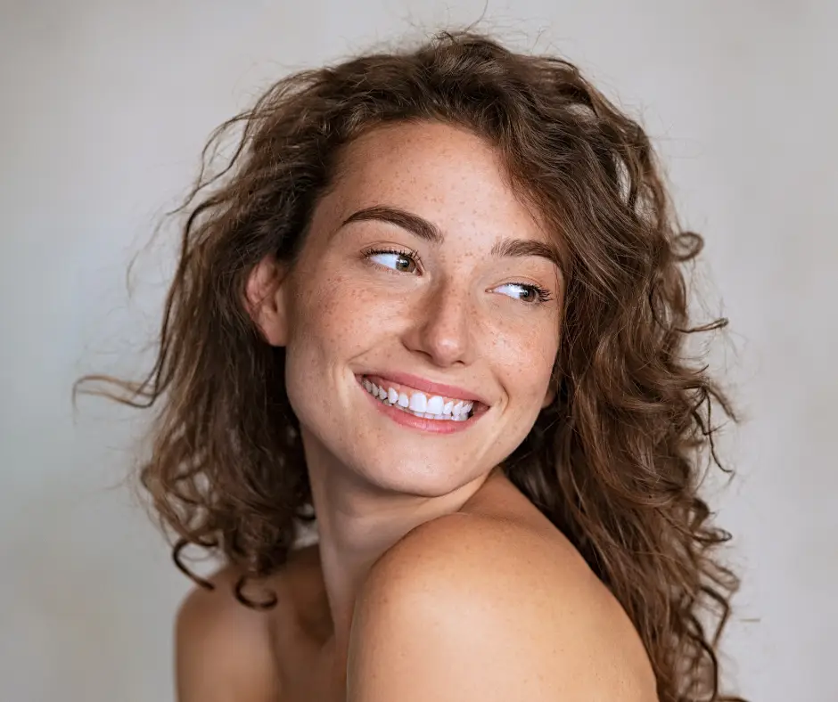 Portrait einer lachenden Frau mit vielen Sommersprossen im Gesicht.